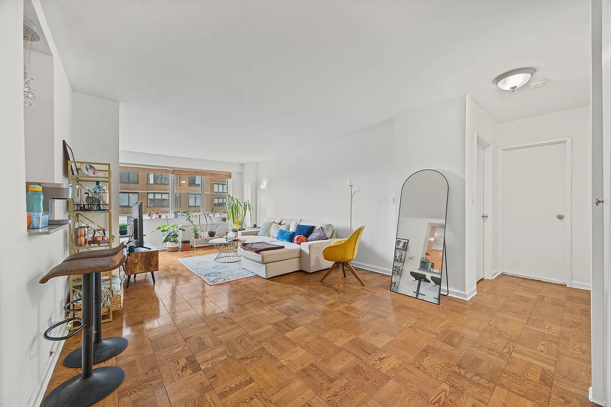 Sunlit living and dining room with parquet floors and a wall of windows
